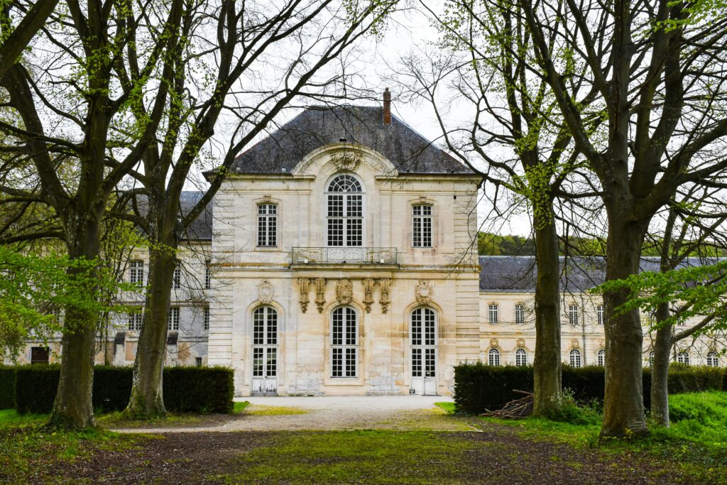 Elegant historic mansion with classical architecture, nestled among trees in France.