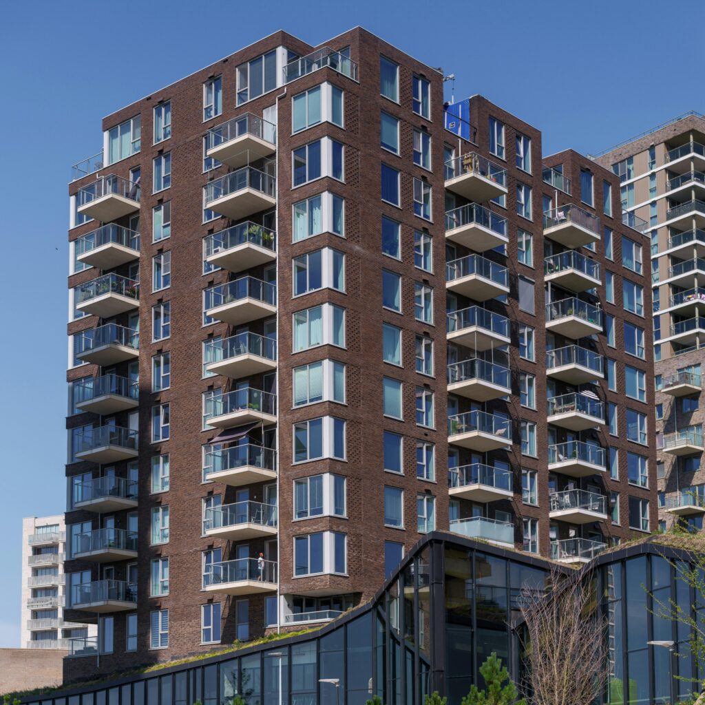 Modern apartment building with distinct balconies in Almere, Netherlands, under clear blue sky.
