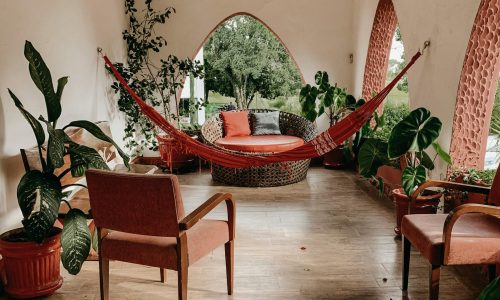 Serene indoor patio featuring a hammock, lush green plants, and comfortable seating for relaxation.
