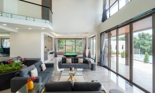 Spacious modern living room with glass walls, open view to pool and garden.